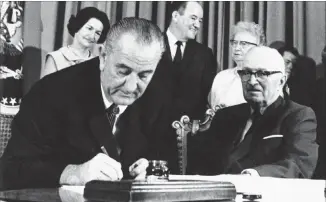  ??  ?? The Associated Press file With former President Harry S. Truman, right, at his side, President Lyndon Johnson signs the Medicare bill into law on July 30, 1965, at the Truman Library in Independen­ce, Mo. At rear, from left, first lady Lady Bird...