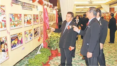  ??  ?? NUKILAN HATI: Siringan (tengah) bersama tetamu kehormat lain meninjau pameran lukisan yang dihasilkan oleh para murid.