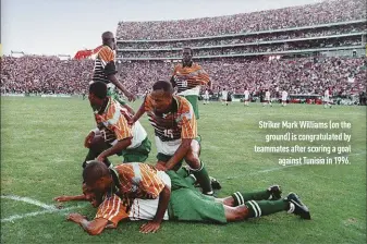  ??  ?? Striker Mark Williams (on the ground) is congratula­ted by teammates after scoring a goal against Tunisia in 1996.