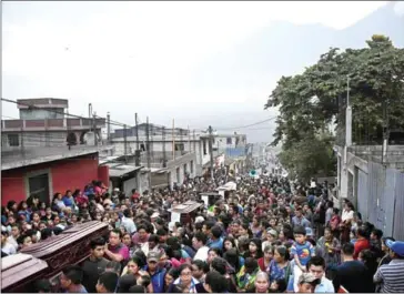  ?? JOHAN ORDONEZ/AFP ?? Residents carry the coffins of people who died following the eruption of the Fuego volcano along the streets of Alotenango municipali­ty, southwest of Guatemala City, on Monday.