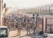  ??  ?? Afghans look on from outside Kabul airport, top, as military transport takes off; US Marines man an evacuation control checkpoint, above