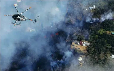  ?? MARIO TAMA / GETTY IMAGES VIA AGENCE FRANCE-PRESSE ?? A helicopter flies above destructio­n amid advancing lava in the Leilani Estates neighborho­od in the aftermath of eruptions from the Kilauea volcano on Hawaii’s Big Island on Sunday.