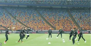  ??  ?? Al Ahly players warm up in an empty stadium as they wait for their opposition to turn up