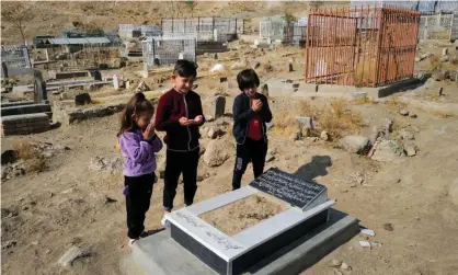  ?? Photograph: Zohra Bensemra/Reuters ?? Ada Ahmadi, 7, with her cousins as they pray by the grave of their relative Farzad, 12, who was killed by the drone in November.