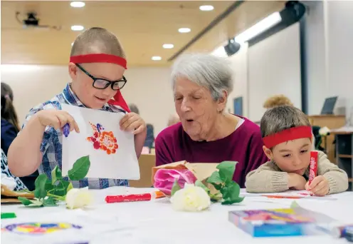  ??  ?? ‘Kindness ninjas’ Josh Moir and Nate Laurin colouring with Elizabeth Conley at a seniors’ centre: a modest but powerful compassion incubator