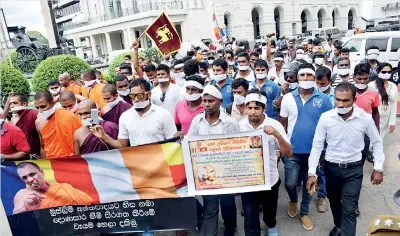  ??  ?? THE ULTIMATE INSULT: Bodu Bala monks and their lay supporters staged a march on Tuesday in Colombo against the imminent arrest of their chieftain Gnanasara with his picture adorning the five colour universall­y accepted flag of Buddhism where not even...