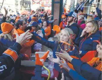  ??  ?? Fabbiana Progar tosses free Broncos hats to the crowd at Friday’s playoff rally in Larimer Square in downtown Denver. Kathryn Scott Osler, The Denver Post