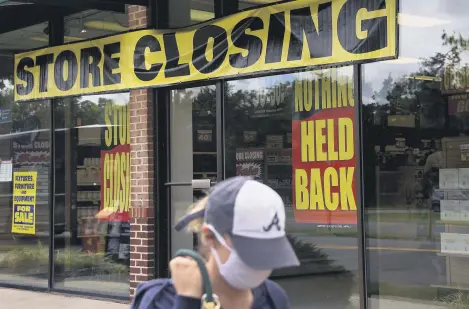  ??  ?? A woman walks past a store closing down due to the economic impact of the coronaviru­s pandemic, Arlington, Virginia, U.S., Aug. 4, 2020.