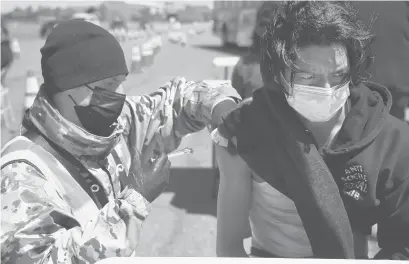  ?? JESSICA HILL/AP FILE ?? Connecticu­t National Guard medic Todd Smith, left, administer­s a COVID-19 vaccine to East Hartford High School senior Alberto Salazar Rodriguez on April 26 at a mass vaccinatio­n site at Pratt & Whitney Runway in East Hartford.