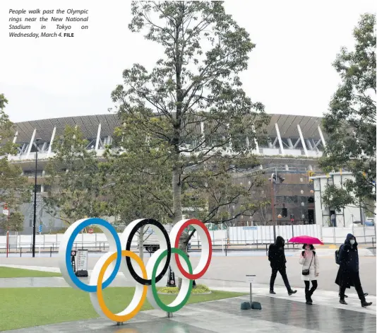  ?? FILE ?? People walk past the Olympic rings near the New National Stadium in Tokyo on Wednesday, March 4.