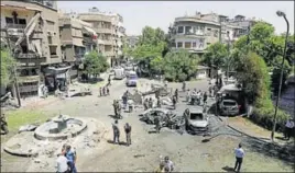  ?? AFP ?? Syrians gather to inspect the damage at the site of a suicide bomb attack in Damascus' eastern Tahrir Square district on Sunday.