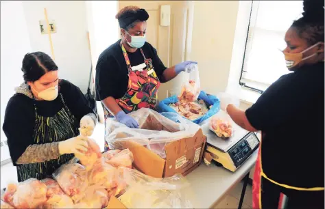  ?? Christian Abraham / Hearst Connecticu­t Media ?? PT Partner organizer Dione Dwyer, center, bags up chicken to give out to residents at the monthly PT Barnum food distributi­on event in Bridgeport on April 4, 2020. Helping Dione at right is Shaurice Bacon, one of many lower-income state residents who feel trapped by Connecticu­t’s lack of affordable housing.