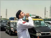  ?? PTI ?? A traffic policeman drinks water to quench his thirst during a spell of heat wave, at Delhi-gurugram expressway in Gurugram