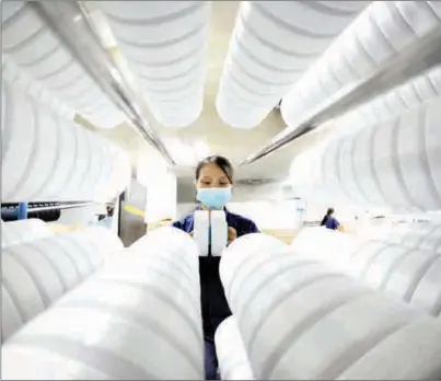  ?? WANG CHUN / FOR CHINA DAILY ?? An employee works on a production line for spandex, a material used in making face masks, in Lianyungan­g, Jiangsu province, on June 29. Employees have been working extra hours to ensure quality and on-time delivery after receiving orders from Italy and Mexico.