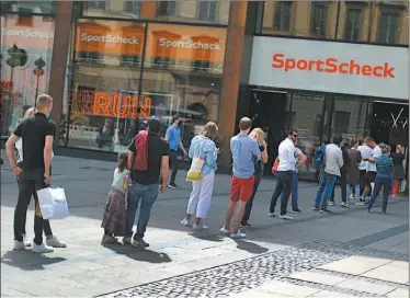  ?? FOTOS: AFP ?? DISTANCIAM­IENTO SOCIAL. Clientes en fila ante un local de productos deportivos en Munich.