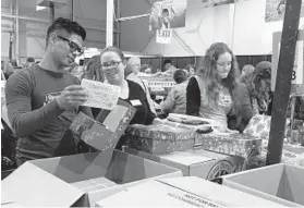  ?? LORRAINE MIRABELLA/BALTIMORE SUN ?? Working in a Columbia warehouse, Luis Gonzalez of Louisville, Ky., and Rachel Tadlock of Lancaster, Pa., pack supplies in shoe boxes to be sent to children around the world.