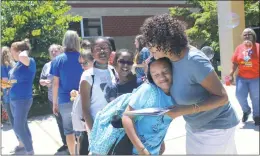  ?? STAFF PHOTOS BY JOHNATHON CLINKSCALE­S ?? Above, J.C. Parks Elementary School guidance counselor Rese Cole of Clinton hugs fifth grader Jaylynne Taylor as she signs her yearbook during the last day of school on June 15 in Indian Head. Also pictured from left are fifth graders Zaiah Mozie and Gabrielle Turner. Below, art teacher Rachael Hall, center left, puts up the peace sign to students waving goodbye as buses pull out on the last day of school at J.C. Parks Elementary on June 15 in Indian Head.