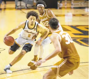  ?? MITCH ALCALA/ASSOCIATED PRESS ?? Oklahoma State guard Cade Cunningham, left, drives past Texas forward Kai Jones, back, and Brock Cunningham, front, during the first overtime Saturday.