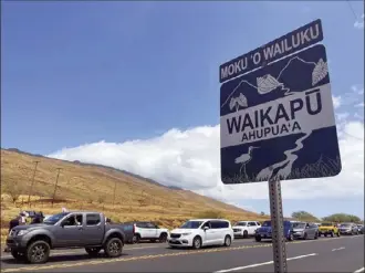  ?? AP Photo / Haven Daily ?? Drivers in West Maui wait in traffic as police open up a roadblock Friday, allowing residents in to check on their homes for the first time after a devastatin­g wildfire destroyed most of the town of Lahaina.