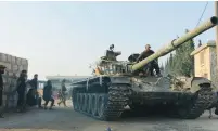  ?? (Ammar Abdullah/Reuters) ?? REBEL FIGHTERS ride a tank in Aleppo, Syria, yesterday.