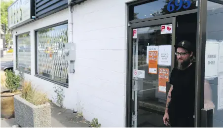  ?? ADRIAN LAM, TIMES COLONIST ?? Employee Myko Hodgson stands at the door of the unlicensed Trees of Eden dispensary on Alpha Street to advise potential customers after the shop was forced to close Wednesday. Trees Cannabis will suspend operations at its six other stores on Aug. 16.