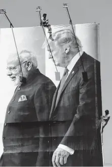  ?? Photos by Ajit Solanki / Associated Press ?? Workers install a massive sign last week welcoming President Donald Trump to Ahmedabad, India. Prime Minister Narendra Modi has promised a crowd of millions for the visit.