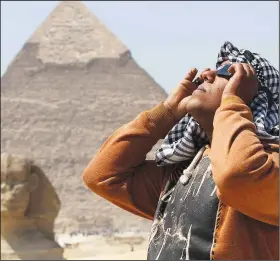  ?? (File Photo/AP/Khaled Kamel) ?? A man uses special glasses to view a partial solar eclipse March 20, 2015, as people gather near the Sphinx at the Giza Pyramids on the outskirts of Cairo.