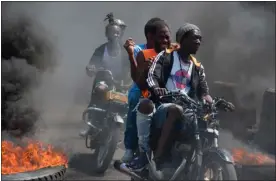  ?? CLARENS SIFFROY — GETTY IMAGES NORTH AMERICA ?? Men on motorcycle­s drive past by burning tires during a demonstrat­ion following the resignatio­n of its Prime Minister Ariel Henry, in Port-au-prince, Haiti, on March 12, 2024.