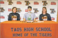  ?? NATHAN BURTON/Taos News ?? Left to right: Retired Head Coach Nancy Call, Taos High School senior Estevan Andres Salazar, and Head Coach Greta Brown sit for a portrait to commemorat­e Salazar’s signing of a letter-of-intent to attend Saint
Norbert College on a swimming scholarshi­p.