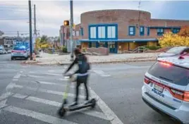  ?? FILE ?? A scooter zips past a school police officer at Carver Vocational Technical High School, three days after three teenagers were injured in a shooting outside the West Baltimore school.