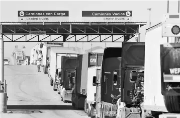  ?? — Reuters photo ?? Trucks wait in a long queue for border customs control to cross into the US at the Otay border crossing in Tijuana, Mexico. The United States said it would work to shrink trade deficits with Canada and Mexico in talks to renegotiat­e the landmark 1994...