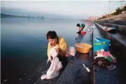 ??  ?? DANDONG: Chinese woman clean their clothes near the Friendship bridge (back top) on the Yalu River connecting the North Korean town of Sinuiju and Dandong in Chinese border city of Dandong yesterday. —AFP