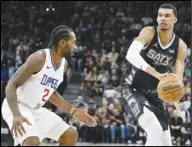  ?? Associated Press ?? The Spurs’ Victor Wembanyama (right) looks to pass around the Los Angeles Clippers’ Kawhi Leonard (2) during the first half on Wednesday in San Antonio.