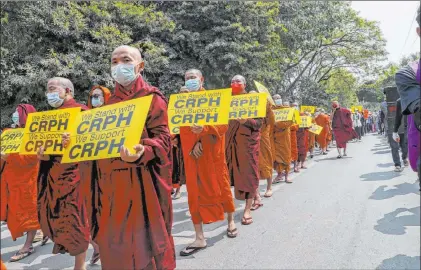  ?? The Associated Press ?? Buddhist monks and other anti-coup protesters display placards during a march Wednesday through Mandalay, Myanmar.
