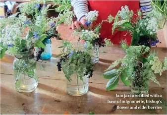  ??  ?? Jam jars are filled with a base of mignonette, bishop’s flower and elderberri­es