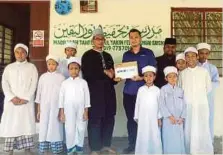  ??  ?? MOHD Hafiz (dua dari kanan) menyerahka­n zakat perniagaan kepada Alias di Madrasah Tahfiz Nurul Yakin di FELDA Sungai Sayong, Kulai.