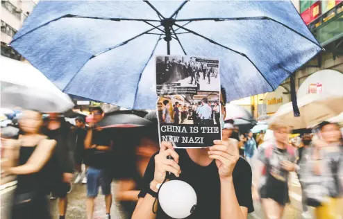  ?? MANAN VATSYAYANA / AFP / GETTY IMAGES ?? Protesters walk along a street during a rally in Hong Kong on Sunday, in the latest opposition to a planned extraditio­n law
that has since morphed into a wider call for democratic rights in the semi-autonomous city.