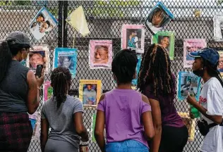  ??  ?? Melissa Brooks, from left, Jordan Brown, Jazmine Brooks, Shari Moore and Laila Brooks, all of Baltimore, study photos in August on a fence near the White House of Black people killed by police.