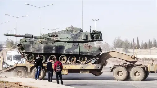  ??  ?? A photo made available by the Dogan News Agency shows Turkish military trucks transporti­ng armored vehicles to reinforce the border units in Sanliurfa close to the Syrian border on Tuesday. (AFP)