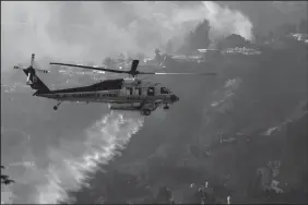  ?? GENARO MOLINA/LOS ANGELES TIMES FILE PHOTOGRAPH ?? A helicopter does a water drop against a row of homes threatened by the Skirball Fire in Bel Air.