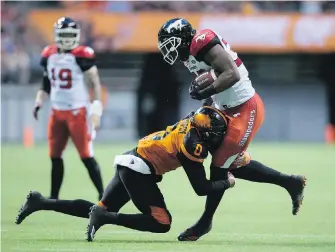  ??  ?? Calgary Stampeders’ Jerome Messam, right, is tackled by B.C. Lions’ Loucheiz Purifoy during the first half of their CFL match in Vancouver on Friday. Play was still in progress at press time.