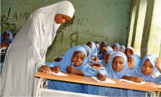  ??  ?? Class teacher, Hajiya Adama Kabir, with pupils of Central Primary School Gamawa, Bauchi State, writing on the sets of school furniture provived by MTN Foundation
