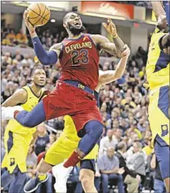  ??  ?? LeBron James drives to basket in traffic as Cavs even series Sunday.