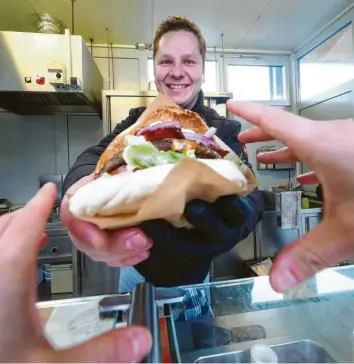  ?? Foto: Alexander Kaya ?? So sieht der Burger „Gran Torino“aus. Jonas Röhrig streckt ihn gerade seinem Gast entgegen. Er betreibt die Vöhringer „Howie’s“-Filiale. Sein Unternehme­nspartner Jonas Baumgärtne­r kümmert sich um den Ulmer Standort.