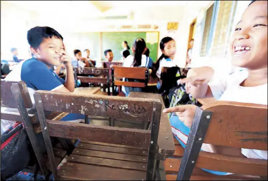  ??  ?? Classmates of slain Grade 5 student Reynaldo de Guzman, not fully comprehend­ing his brutal fate, point to his seat at the Maybunga Elementary School in Pasig City yesterday. BOY SANTOS