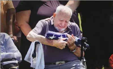  ??  ?? Walter Wilkins tears up June 26 while holding an American flag presented to him by the Army at his brother’s funeral.
