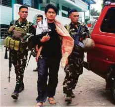  ?? AFP ?? Soldiers escort Maute group member Hassim Balawag Maute alias Apple Jehad to a military vehicle in Marawi City. He along with 22 others were freed on Saturday by their comrades.