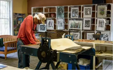  ??  ?? ABOVE Man and machine: local artist Tony Kietzmann plans his next piece atop this lithograph­y press.