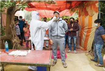  ?? — AFP ?? A medical worker collects a swab sample from a man for a RT-PCR Covid-19 coronaviru­s test in Ghaziabad. photo