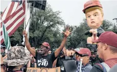  ??  ?? Simpatizan­tes de Trump protestan frente a un muñeco del presidente.